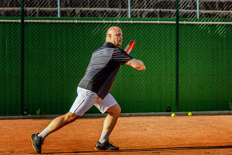 Middle-aged man utilizing crossover step during tennis match